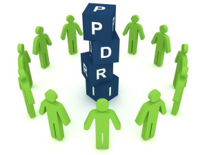 A group of 3D stick figures, circled around a tower of blocks that spell out PDRI